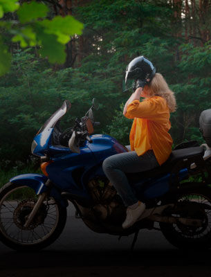 Foto de uma mulher retirando capacete em uma moto